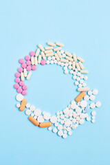 creative medicine compositions. the frame of tablets and capsules, different shapes on a light blue background. vitamins for skin, hair, and nails. flat lay, vertical frame