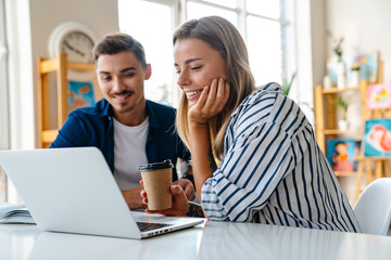 Young caucasian man and woman studying with laptop in classroom