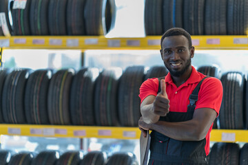 Portrait of happy African male auto mechanic in the background of a car tires service concept