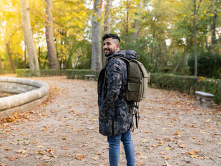 man with backpack and hood in forest, nomad traveler