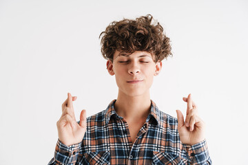 Pleased curly guy posing with fingers crossed for good luck