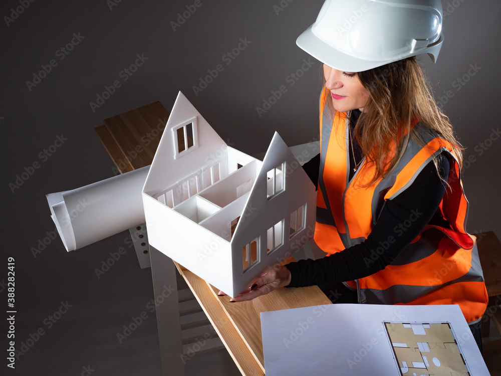 Poster architecture business. woman in uniform of a builder. woman architect holding a mock-up of house. po