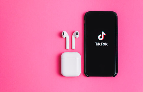 TikTok App Logo On The Screen And AirPods Isolated On Pink Background. Rostov-on-Don, Russia. 11 September 2020