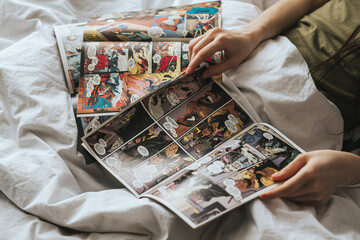 Naklejka premium Woman reading comic book in the bed at home. Rostov-on-Don, Russia. 14 April 2020