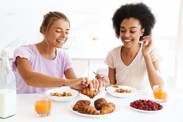 Nice multicultural girls smiling while doing makeup together