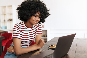 Fototapeta na wymiar Smiling african american student girl doing homework with laptop