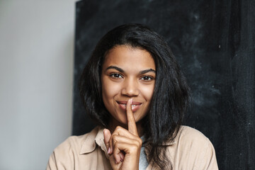 Happy african american woman showing silence gesture on camera