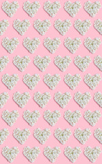 Valentine's day layout. repeating heart pattern of white hydrangea flowers on a pink background. vertical frame, flat lay, top view