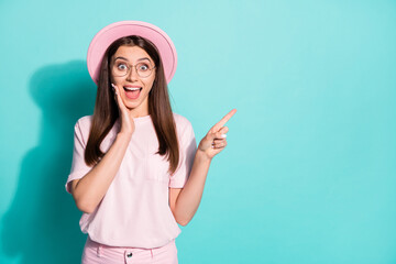 Photo of attractive girl wear pink t-shirt vintage cap pointing one finger arm cheekbone empty space isolated teal color background