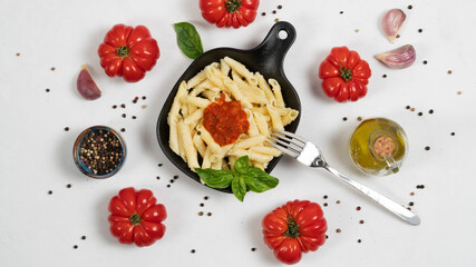 Tasty penne pasta on a pan with bolognese sauce tomatoes peppercorns garlic and basil. Top view.