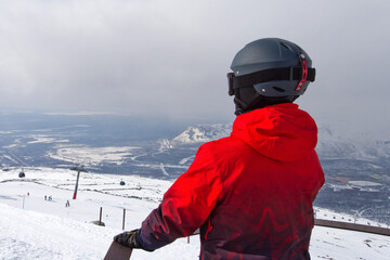 the snowboarder enjoys the beautiful view of the snow-white mountains of the ski resort