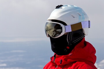 head of a snowboarder in a ski helmet and mask against the backdrop of snow-white mountains