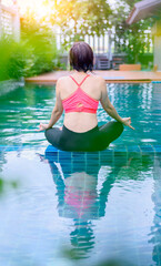 Asian woman yoga breathing and meditation alone at swimming pool at home. Outdoor exercise and...