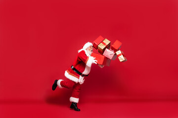 Santa Claus with a lot of gifts on a red background. © neonshot