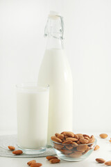 A glass with almond milk and the bowl with almonds