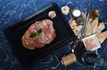 Raw marinated meat on cooking pan, dark stone background, top view. ingredients for roasting