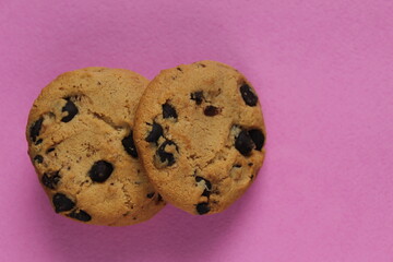 cookies with chocolate drops are stacked top view on a pink background of copy space