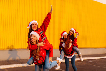 group of excited young women wearing santa claus hats have fun and ride each other in the fresh air. New Year, celebration