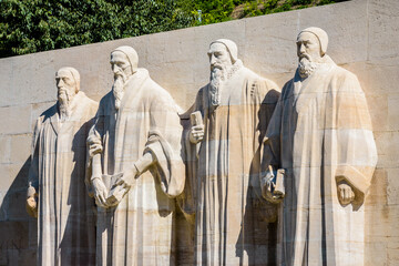 The four statues at the center of the Reformation Wall in the Parc des Bastions in Geneva, Switzerland, representing John Calvin and the Calvinism's main proponents, on a sunny summer day. - obrazy, fototapety, plakaty