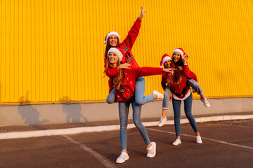 group of excited young women wearing santa claus hats have fun and ride each other in the fresh air. New Year, celebration