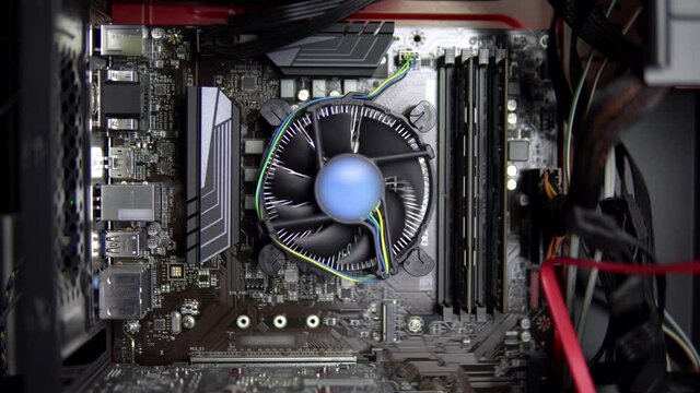 The processor cooler on the motherboard is spinning. CPU cooling system on pc. View of the computer from the inside.