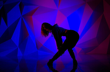 Woman dancing on the background of a beautiful multicolored wall. Sexy slim lonely girl with long...