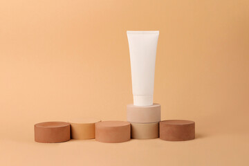 Empty cosmetic tube standing on the geometrical podiums.Beautiful earth colors.Concept of the tonal foundation with different types of skin.Good for placing your product.