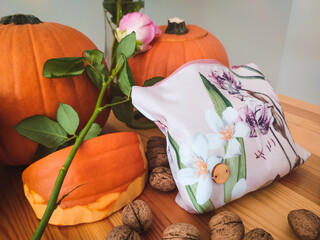 Handmade make-up bag surrounded by walnuts, roses and pumpkins.