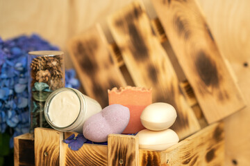 Handmade body cream, bath bomb and soap are in a wooden box.  glass bottle with flavored dried flowers. Sprig of hydrangea flowers. Spa salon. Sauna set