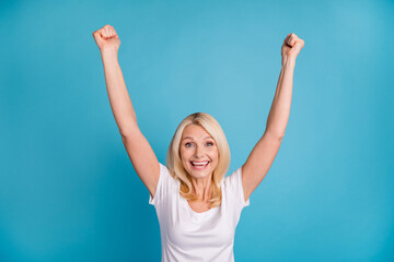 Photo of delighted old woman lucky win raise fists scream wear good look clothes isolated over blue...