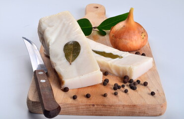 Salted lard with bay leaves and onion on the kitchen board. Salted homemade lard