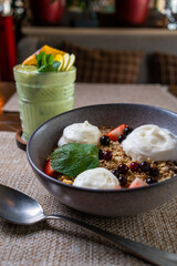 oatmeal porridge in ceramic bowl with fresh ripe berries and mint over rustic wooden background