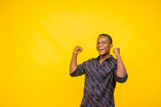 portrait image of a young exciting african man. young african man smiling and raising up both hands for joy.
