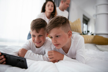 Two little brothers are playing games on the phone. Beautiful boys enjoying at home.