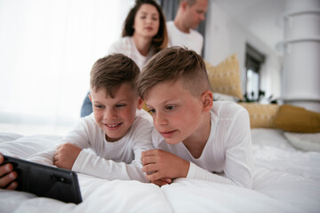 Fototapeta premium Two little brothers are playing games on the phone. Beautiful boys enjoying at home.