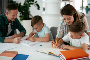 Obraz premium Parents helping the kids with their homework. Litlle boys learning at home.