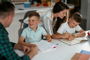 Parents helping the kids with their homework. Litlle boys learning at home.