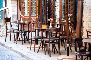 Fototapeta na wymiar Wooden tables and chairs in a cafe on the street of old Europe