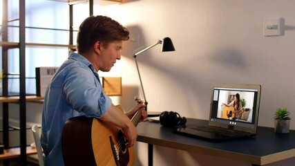 music, e-learning and technology concept - young man or musician with laptop computer learning to play guitar with teacher online at home - Powered by Adobe
