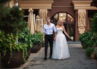 Young happy couple in love together on their wedding day stroll in blooming green garden