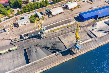 Loading coal mining in port on cargo tanker ship with crane bucket of train. Aerial top view.