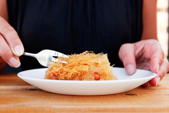 Piece of kadaif dessert on white plate.
