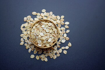 Obraz na płótnie Canvas Barley flakes in a round wooden bowl on a gray background. 