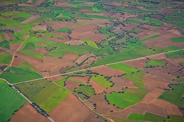 Aerial photo of arable land in Central Spain. View from top of plowed green fields crossed by roads.