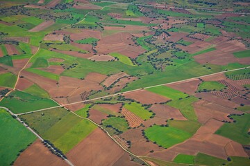 Fototapeta premium Aerial photo of arable land in Central Spain. View from top of plowed green fields crossed by roads.