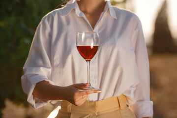 Vintner woman tasting red wine from a glass in a vineyard