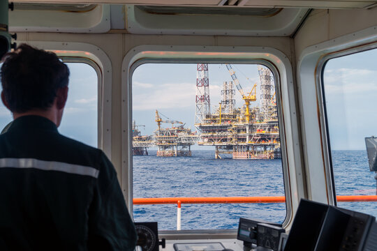 A supply boat captain maneuvering his vessel from forward bridge while heading to a production platform for transferring material and equipment at Terengganu oil field.