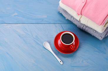 Gray knit sweater Pink and white with coffee cup and spoon placed on blue wooden table - top view