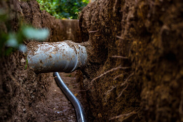 Sewer and water pipe in an excavated trench deep in the ground, close up. Sewerage and water system...