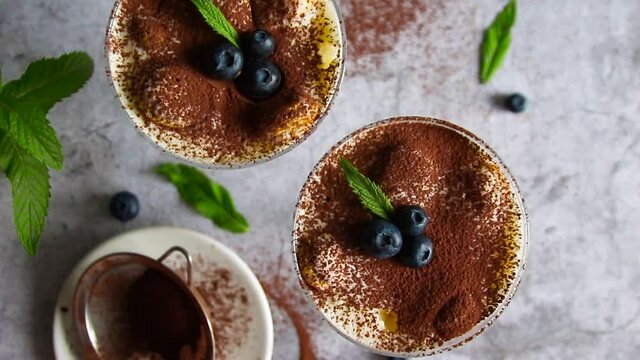 Classic tiramisu dessert with blueberries, mascarpone cheese and espresso coffee in a glass cup
